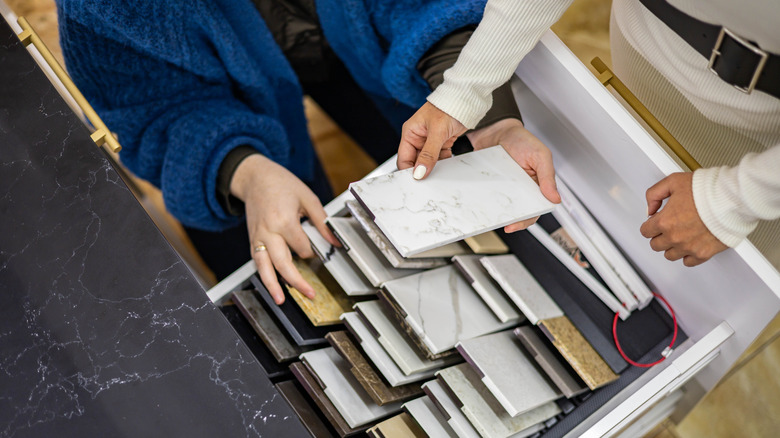 An interior designer showing countertop samples to a customer.