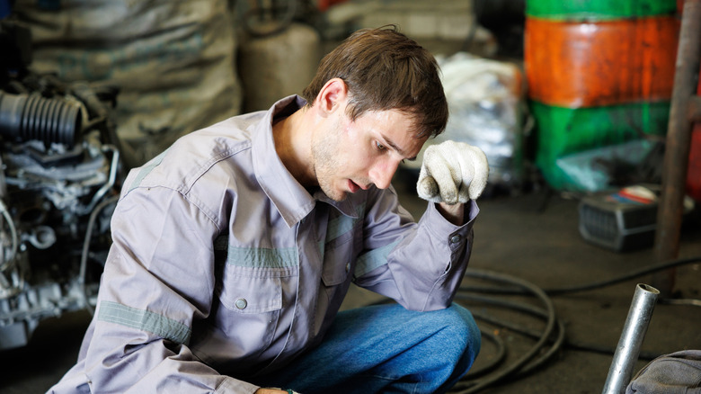 A worker in a hot garage bending over