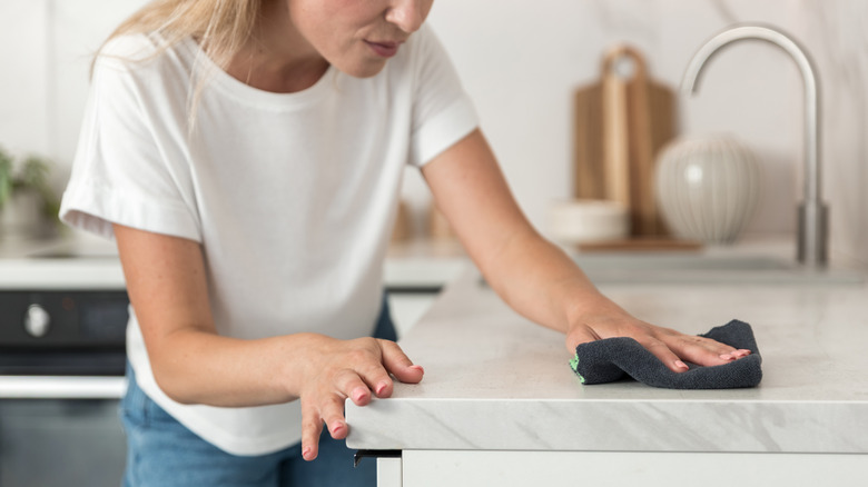 A person wiping a quartz countertop with a cloth