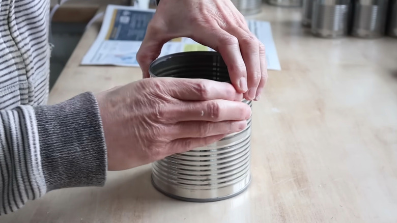 hands preparing old coffee can on a wood table