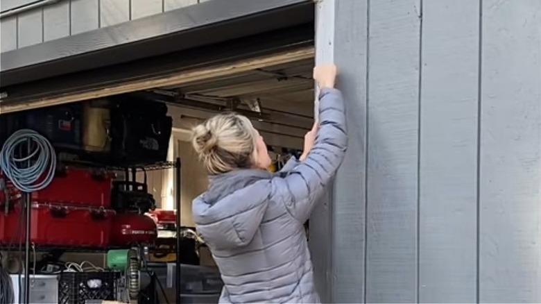 A woman attaches boards to frame her garage door