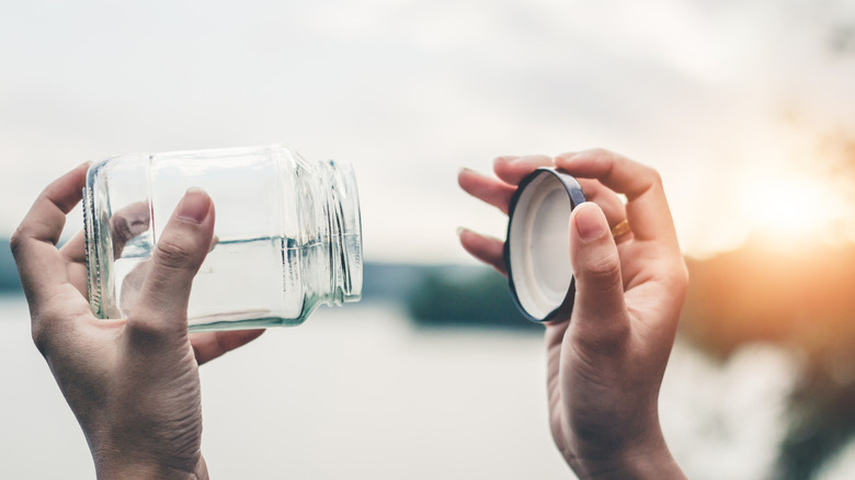 Person holding an empty pickle jar and lid