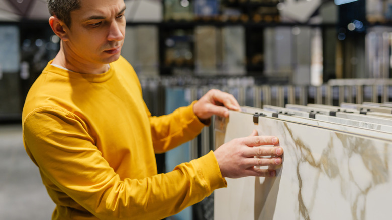 A serious-looking man is looking at countertop options in a store
