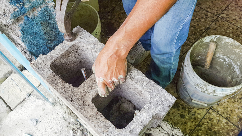 A person builds a wall with cinder blocks