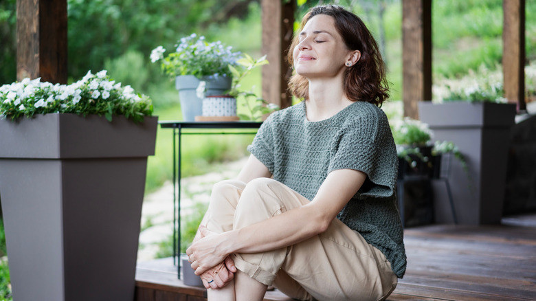 A woman smiles while sitting on her patio surrounded by planters