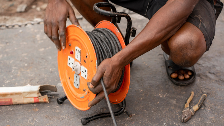 Man kneeling down to reel extension cord