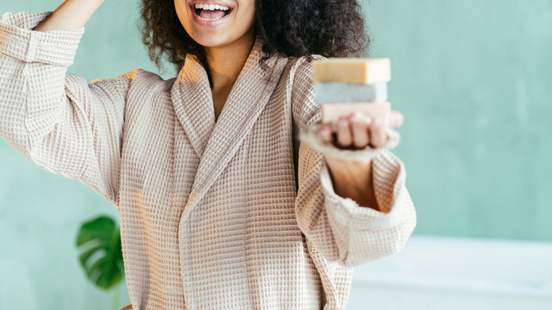 Woman wearing robe holding stack of soap bars