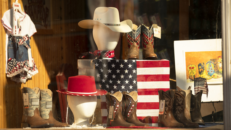 Cowboy hats, boots, and an American flag are on display at a vintage Western ware shop