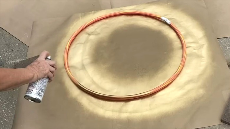 Woman spray painting hula hoop black for DIY project