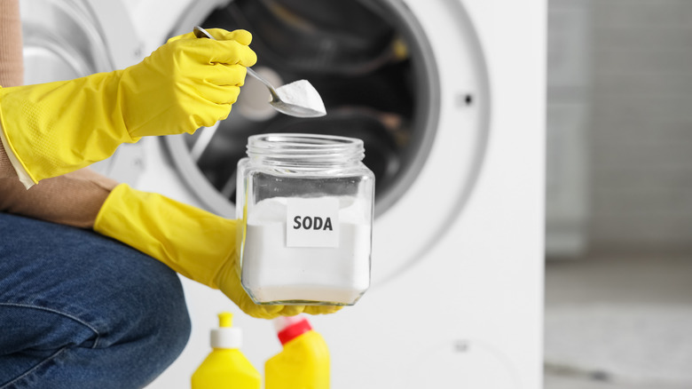 Woman scoops white powder from a jar labeled SODA in a laundry room