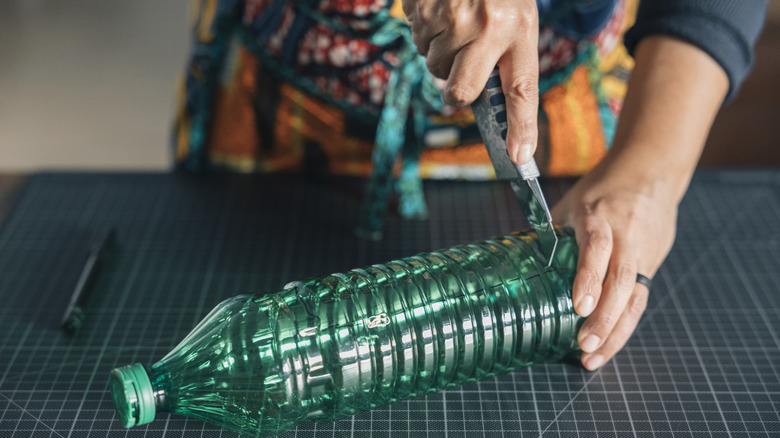 hands cutting a plastic bottle