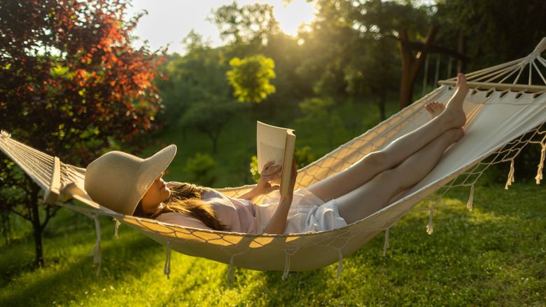 Woman reading in a hammock near greenery
