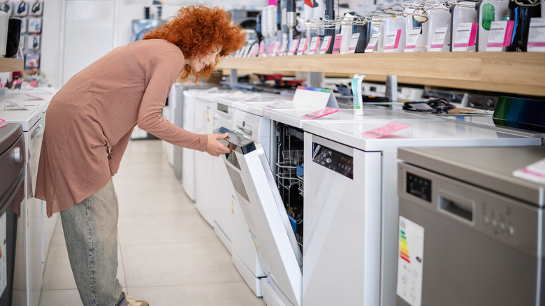 Woman shopping for dishwasher looking inside machine at store