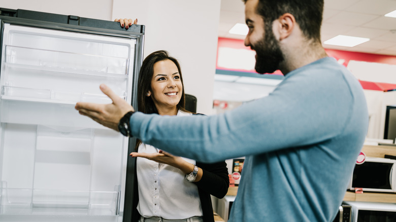 A couple smiles as they shop for a refrigerator