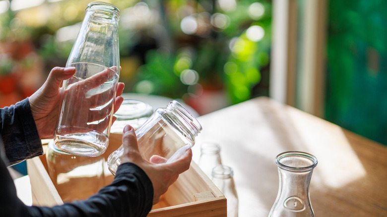 Person holding empty pickle jars over a crate
