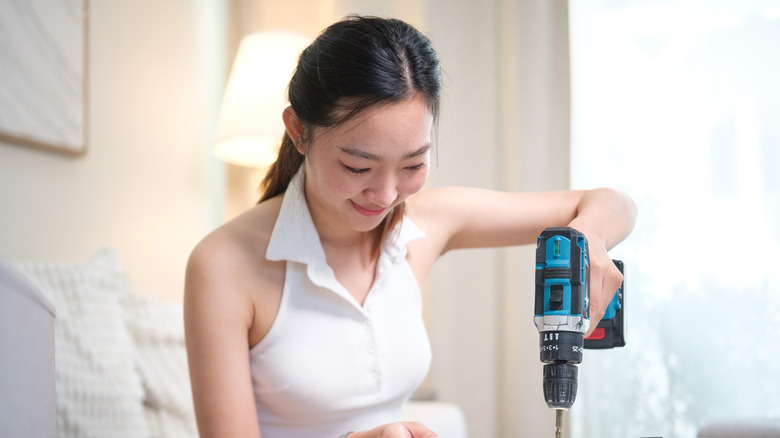 A woman using a drill for a DIY project