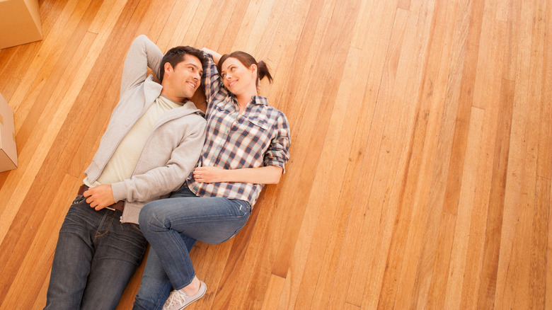 Young couple laying on hardwood floor