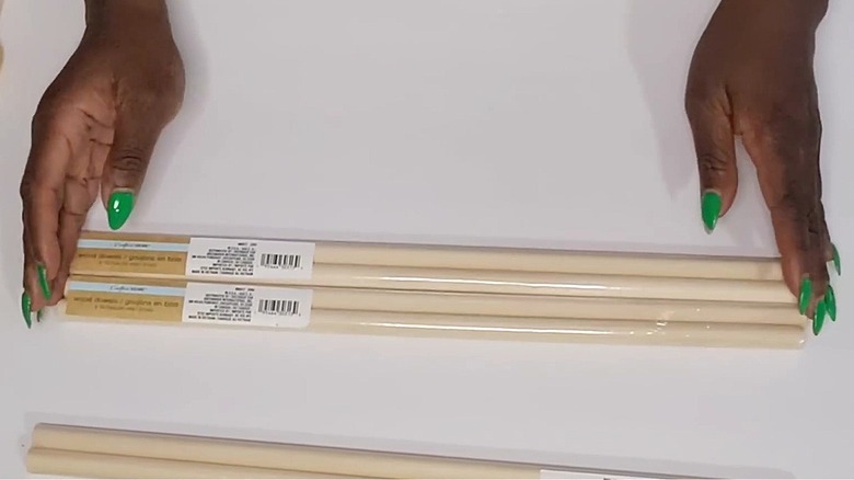 A woman prepares Dollar Tree wood dowels on a table