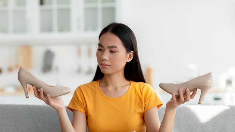 A woman looks concerned as she holds a pair of shoes