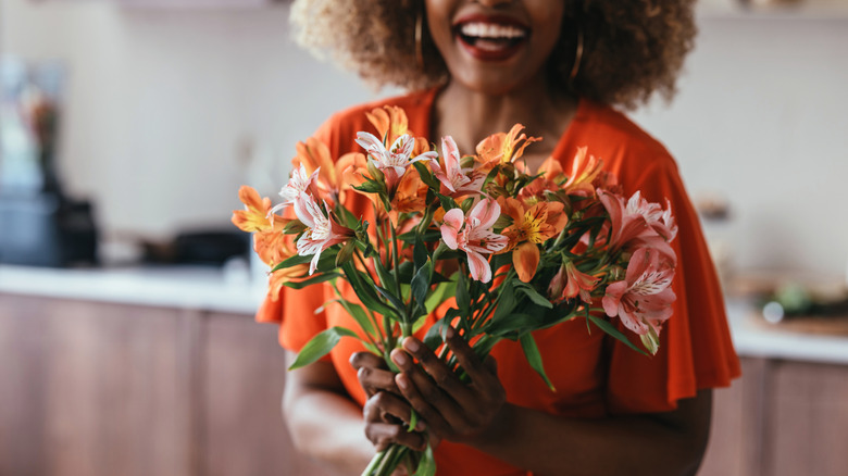 A woman smiles while holding a bunch of flowers