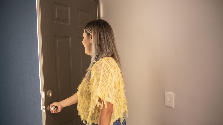 A woman opens a gray builder-grade door
