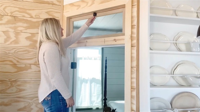 Woman opening transom window over a bedroom door