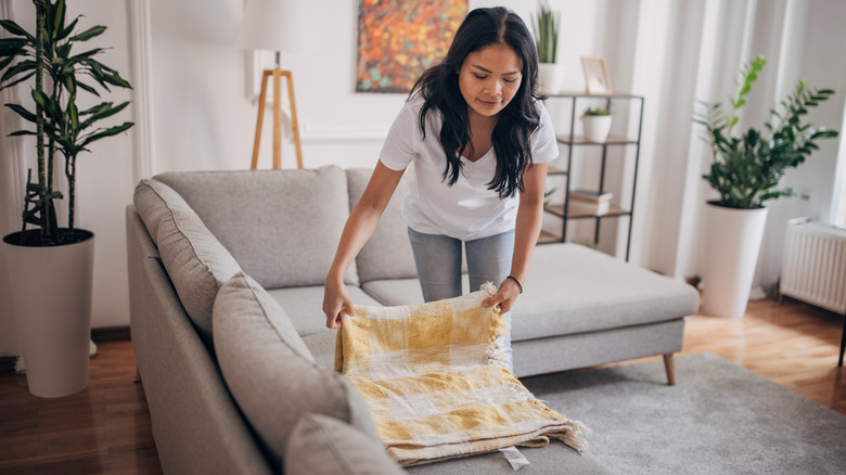 A woman folding a blanket.