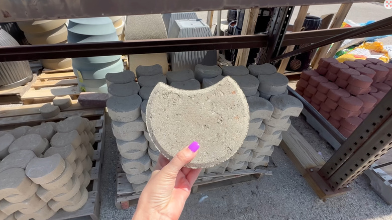 Person holding a rounded paver edging piece at a home improvement store