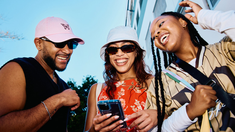 A group of three young adults, laughing together