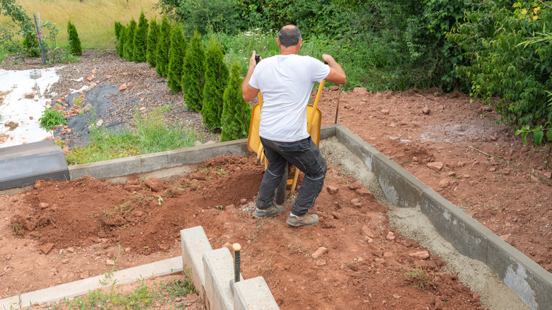 A person pouring dirt inside a retaining wall