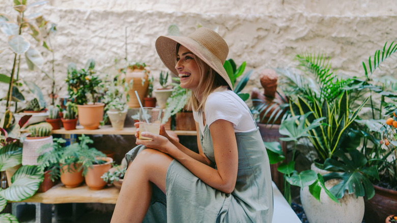 A woman smiles and relaxes on her patio surrounded by plants