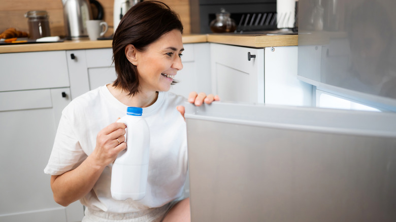 Woman taking milk jug out of the fridge
