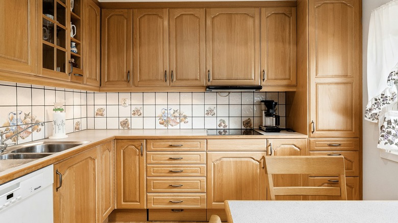 Red oak kitchen cabinets against a white tile backsplash