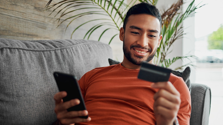 A person shopping on a phone and holding a credit card
