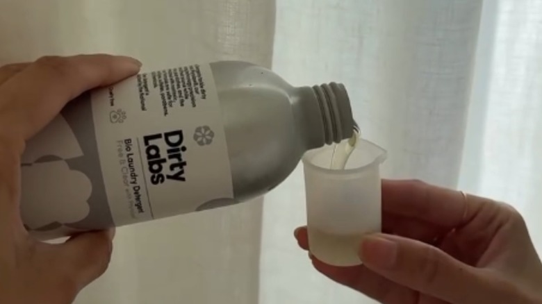 A pair of hands pouring Dirty Labs detergent from the bottle