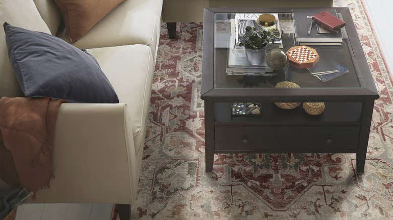 A dark wood coffee table sits on a JÄRNVÄG Rug from IKEA