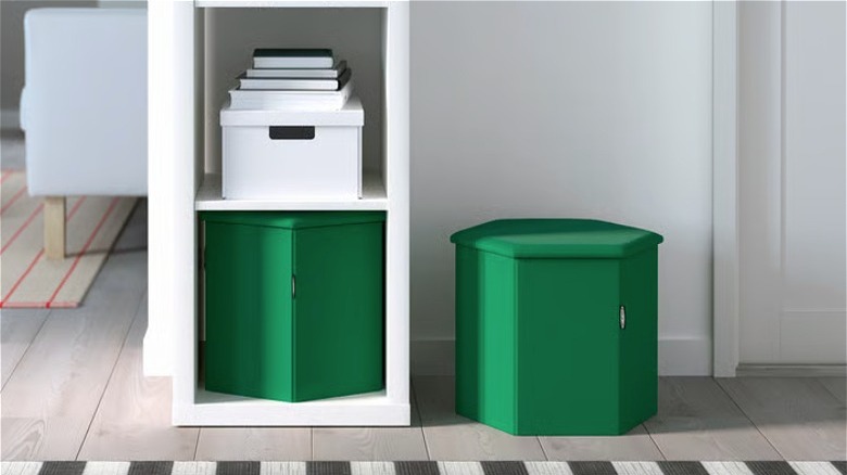 A green KJUGE pouf on an entryway floor and another in a narrow bookcase