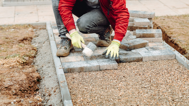 Man installing pavers over a proper base of gravel and sand