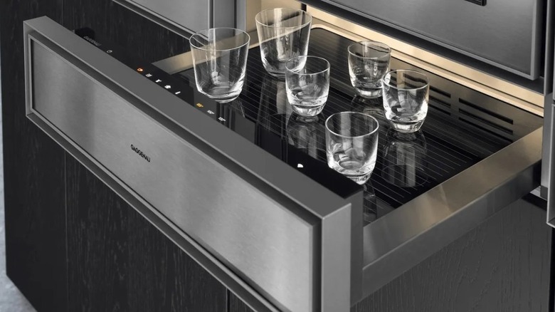 A stainless steel warming drawer made by Gaggenau, opened with with glassware.
