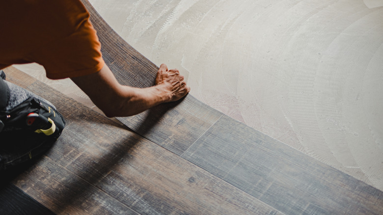 An installer glues down luxury vinyl plank flooring