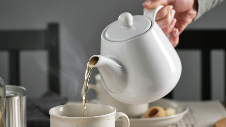 person pouring a cup of tea with a white LYSRÄKA teapot