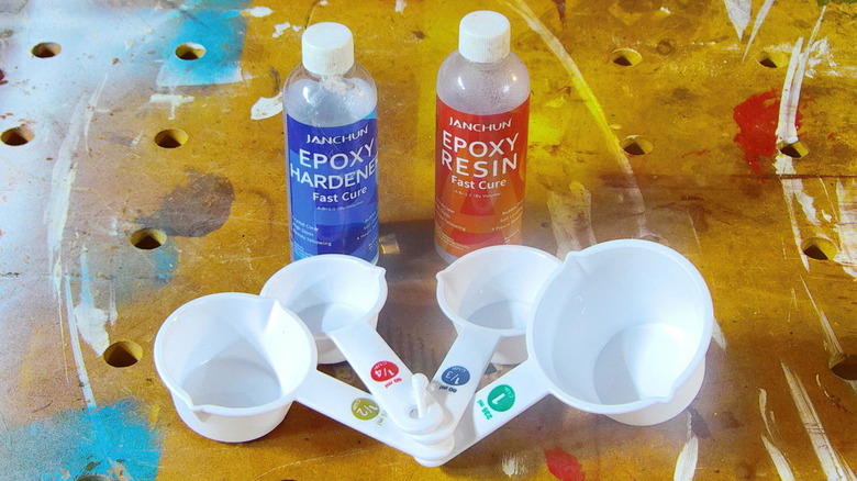 Bottles of epoxy resin and hardener, and measuring cups