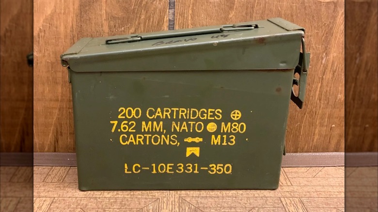 An old metal ammo box sits on a wooden floor