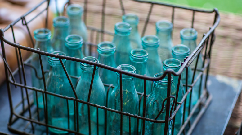 Vintage glass bottles are stored in a wire milk crate