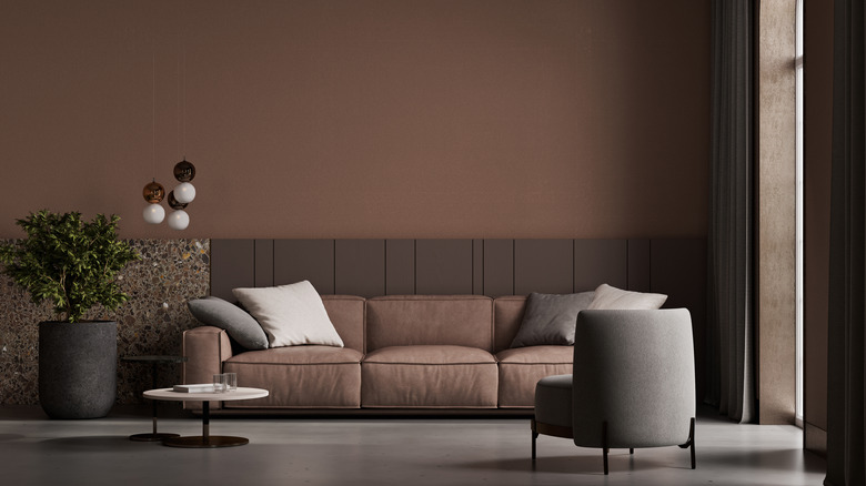 A dark, espresso-colored living room with brown sofa and gray chairs