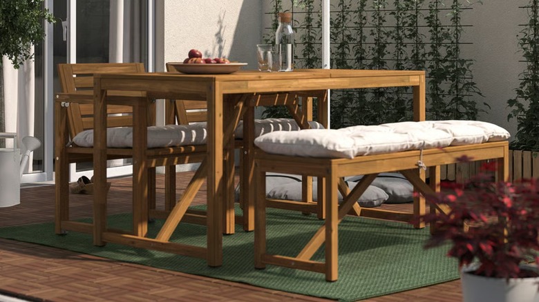 A thin, green MORUM rug is placed under outdoor furniture