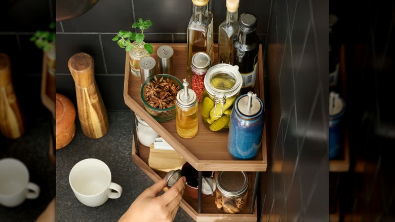Woman taking something out of a two-tier NÅLBLECKA countertop organizer in a kitchen