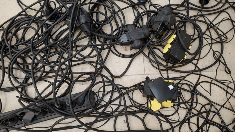 Chaotic mess of tangled electrical extension cords and power strips