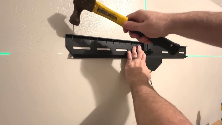 Person installing no-stud wall mount into drywall