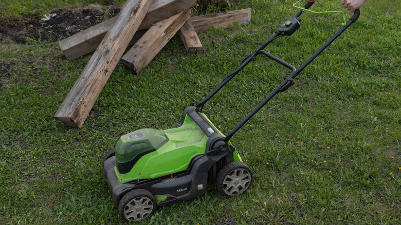 A small green mower is cutting grass unevenly